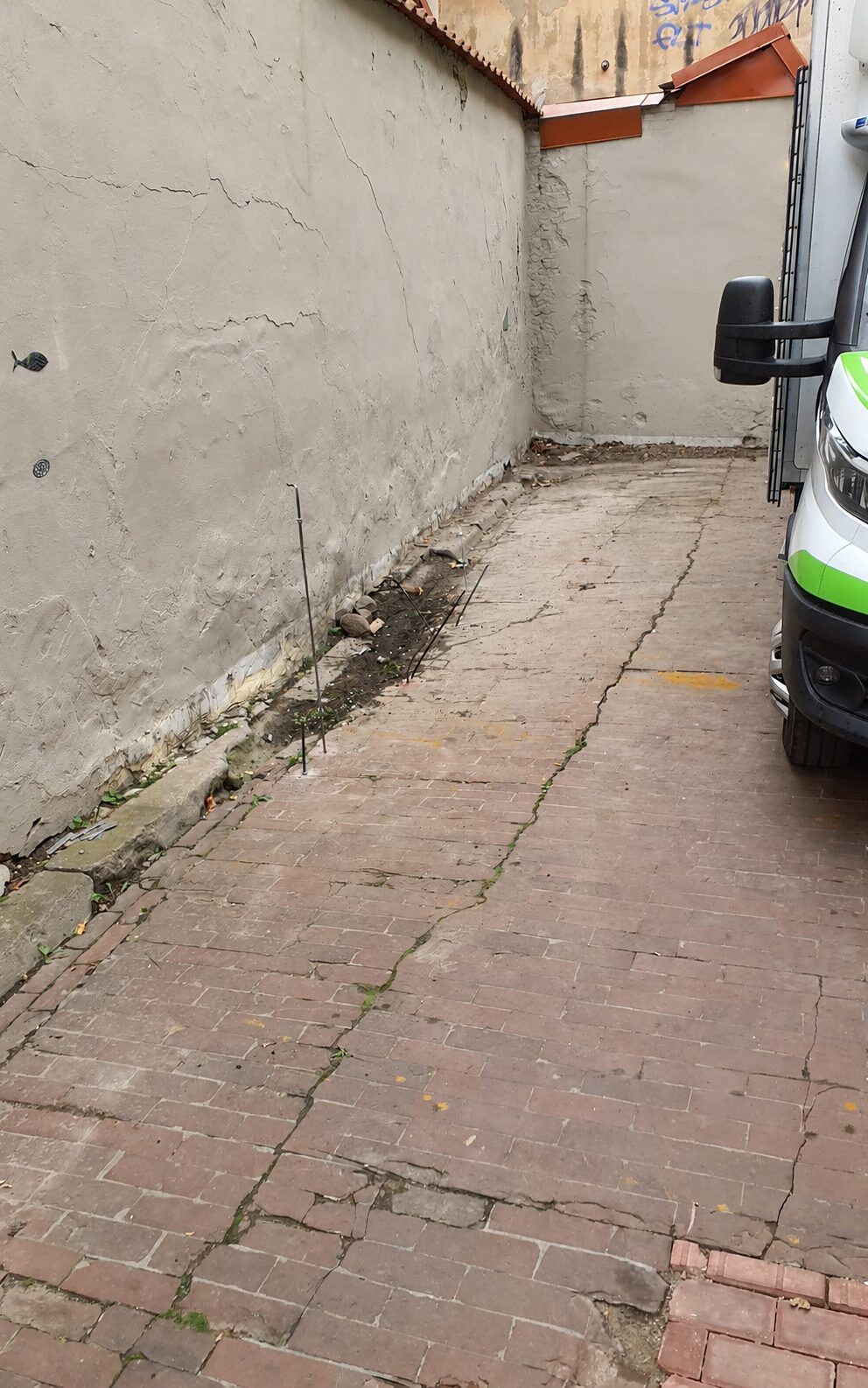 Historic building foundation stabilisation site with visible wall cracks and paved ground settlement